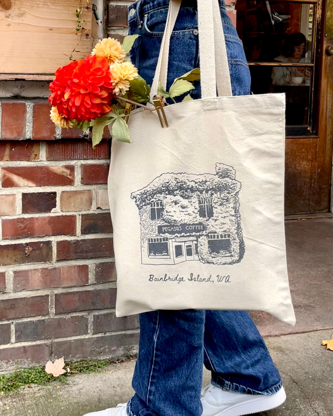 Person walking in front of Pegasus Coffee House holding a Pegasus Coffee Tote Bag